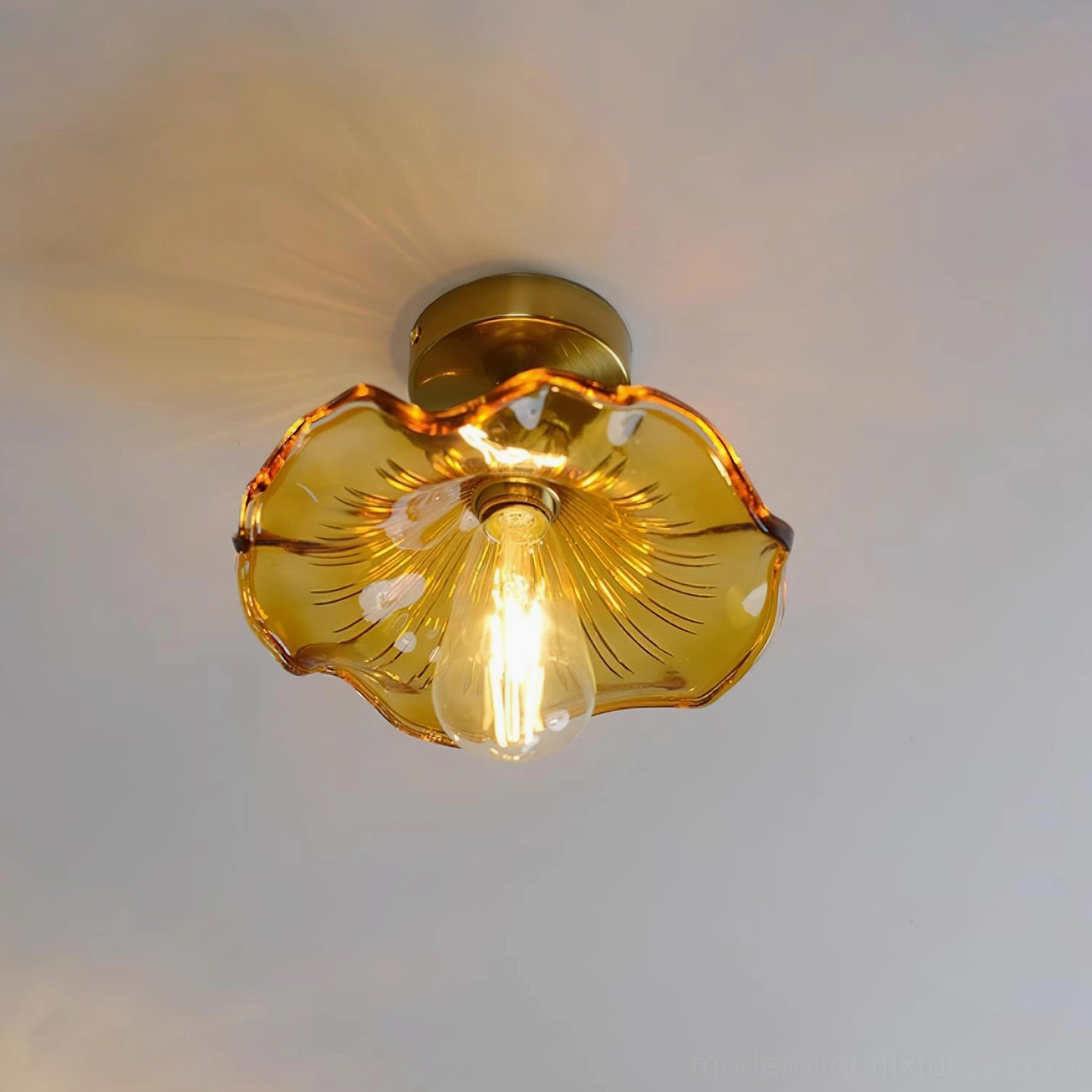 Amber wavy glass ceiling fixture with warm tinted shade, brass mounting base, overhead mounted