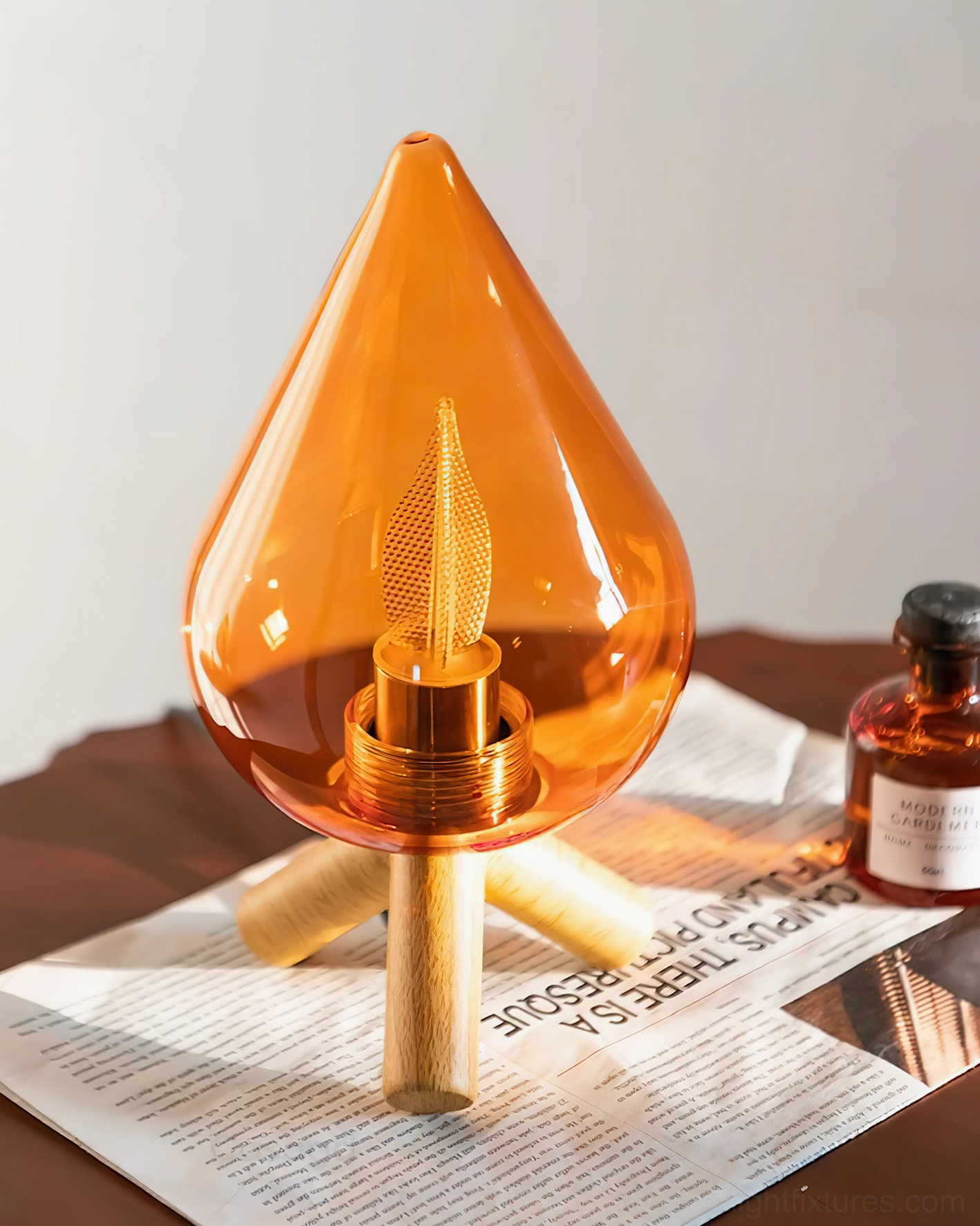 Scandinavian table lamp top-front angled perspective on dark wood side table with magazine and decorative apothecary bottle, styled home setting