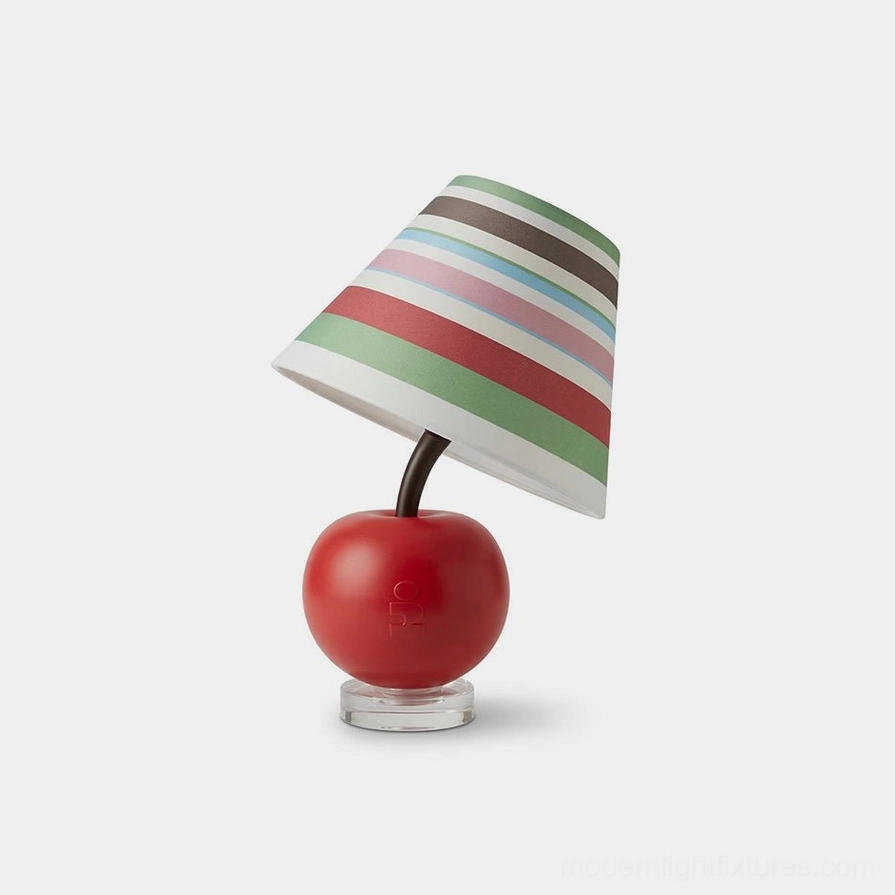 Apple-shaped red resin table lamp with striped fabric shade and clear acrylic base, side oblique studio view