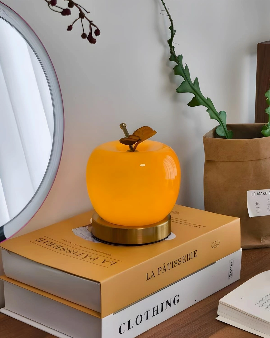 Orange apple lamp on vanity desk with fashion magazines and decorative accents, contemporary interior styling