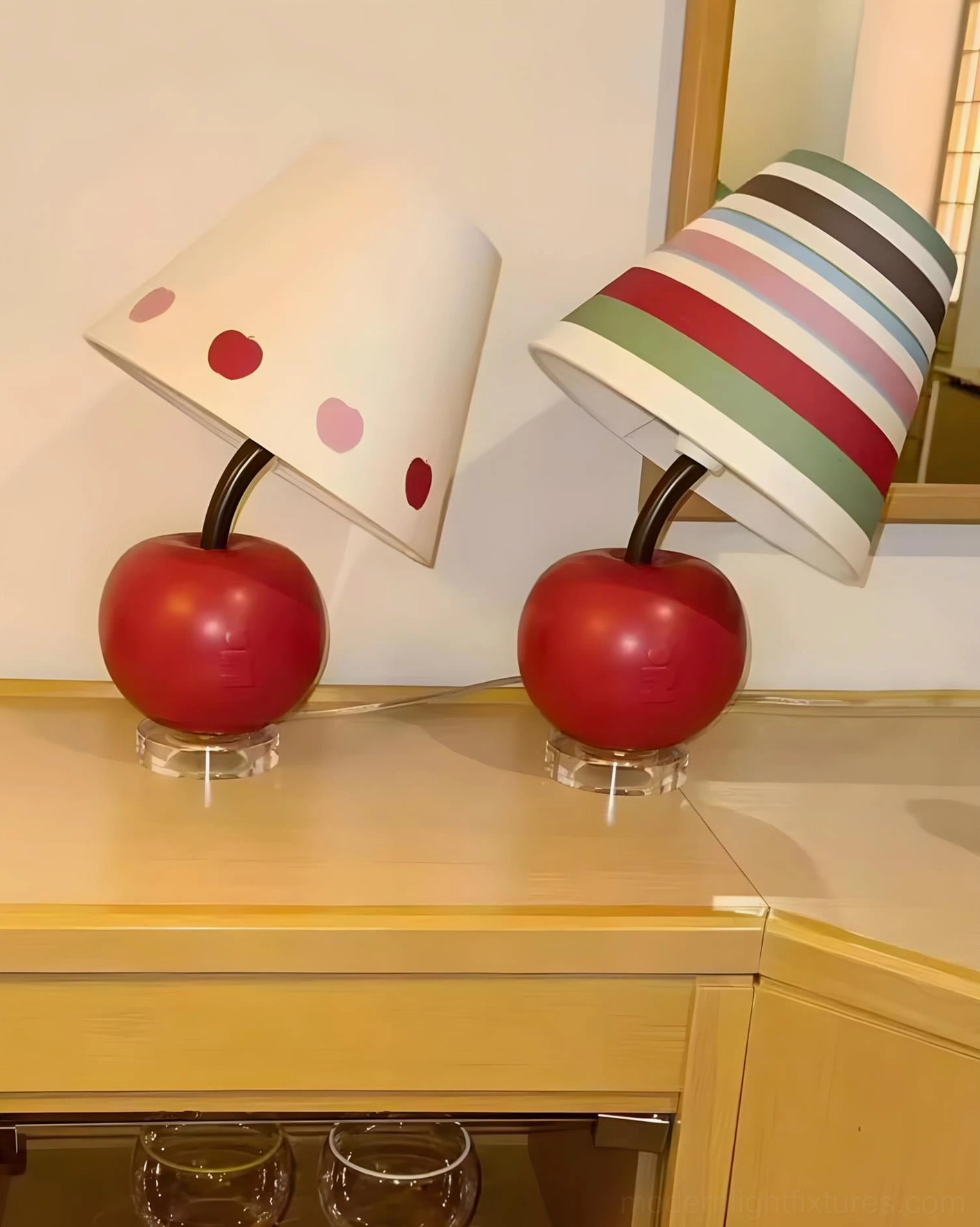 Two apple-shaped table lamps with different shade patterns - striped and polka-dot white design on kitchen cabinet counter
