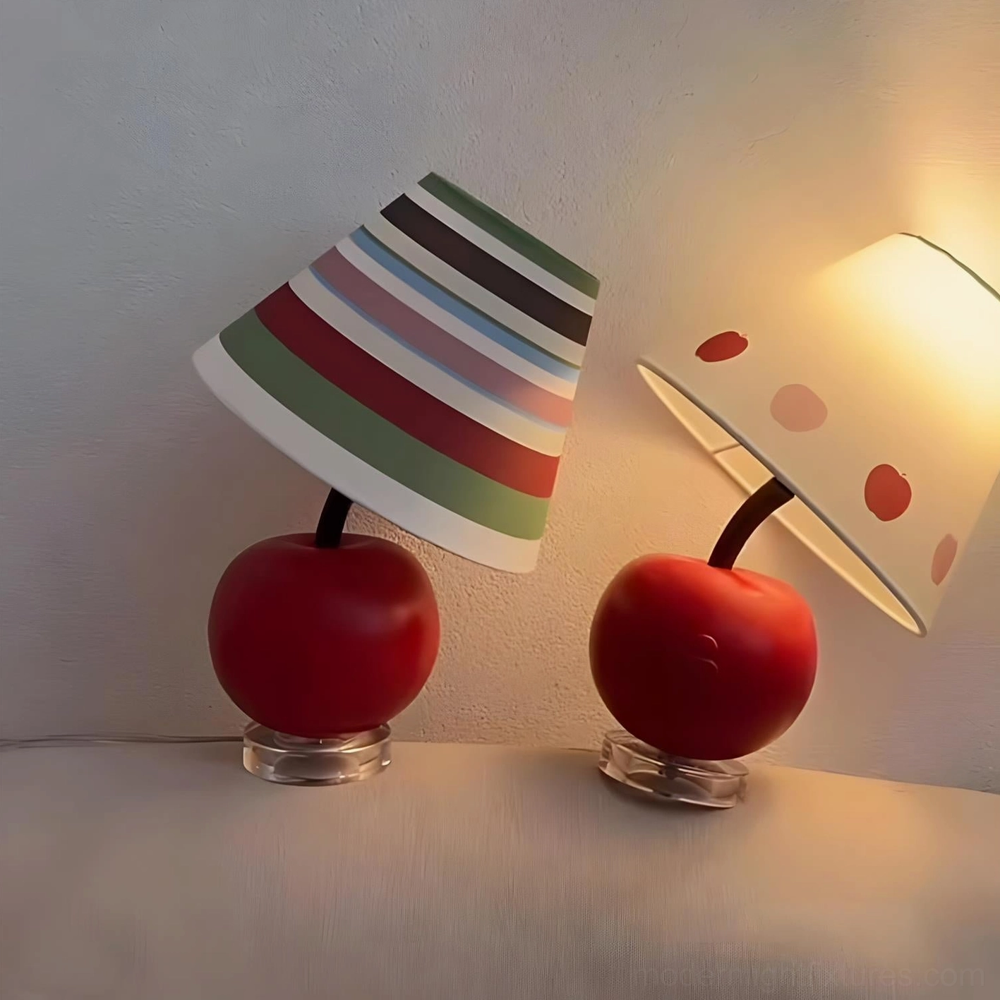 Two lit apple-shaped table lamps with warm ambient lighting on soft bed surface, cozy bedroom scene