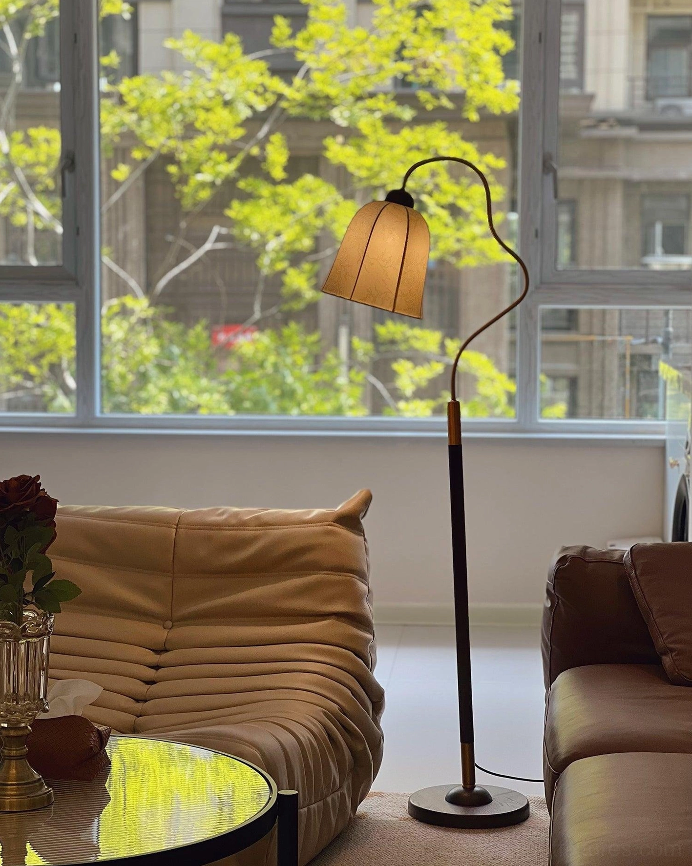 Arc floor lamp with brass trim details on dark wood pole, positioned beside accent seating furniture