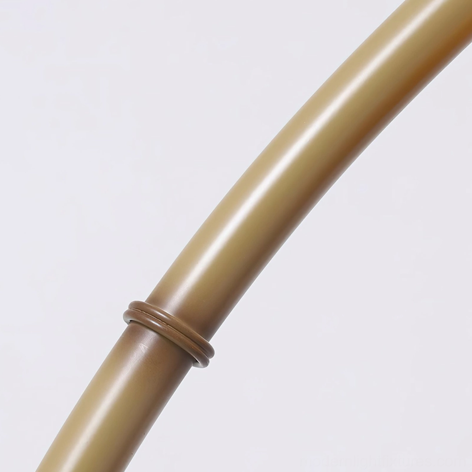 Modern arc floor lamp close-up showing details of marble base, yellow metal curve, and caramel glass shade construction