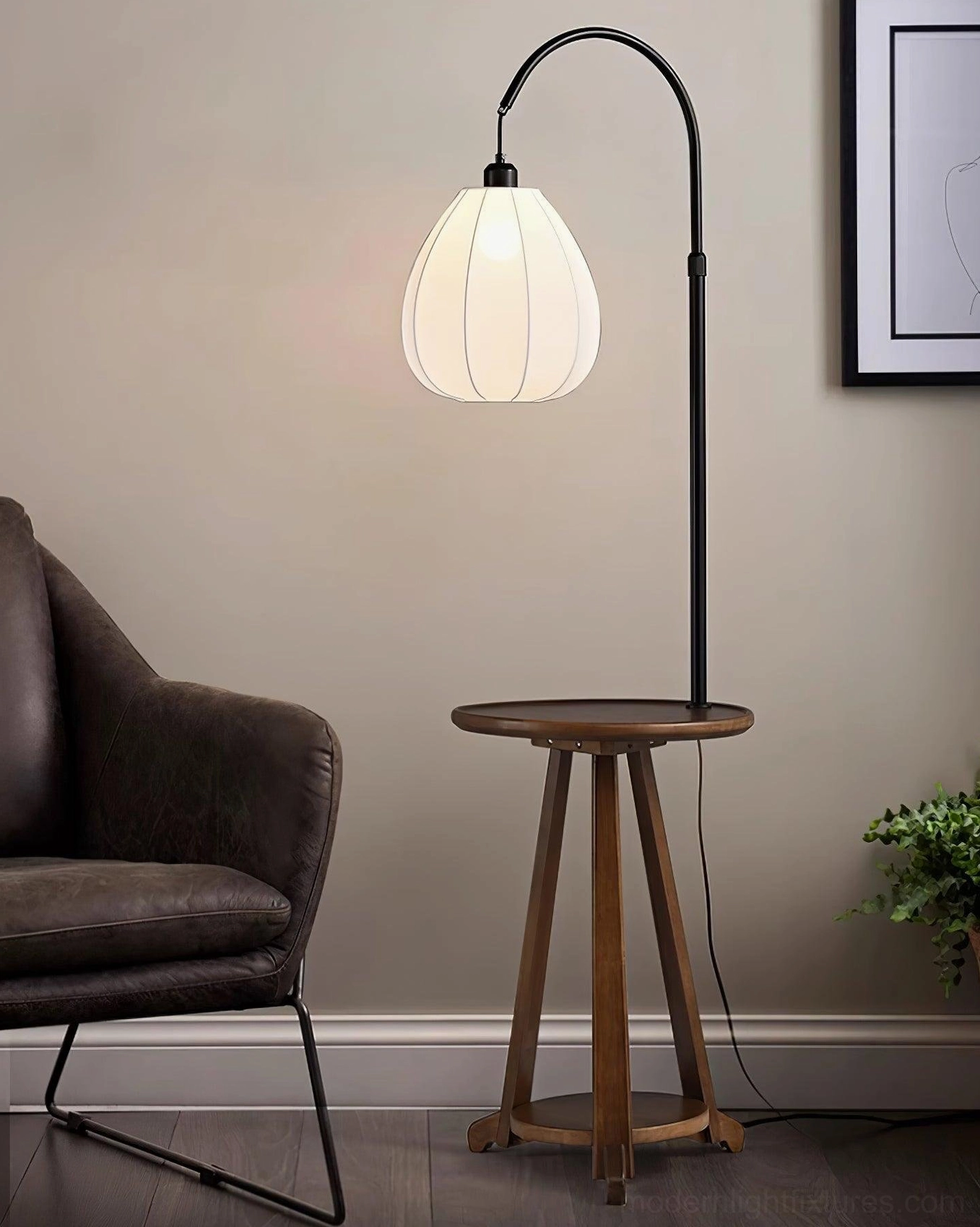Arc floor lamp with wooden side table in living room, dark brown leather armchair, framed wall art, plant decor