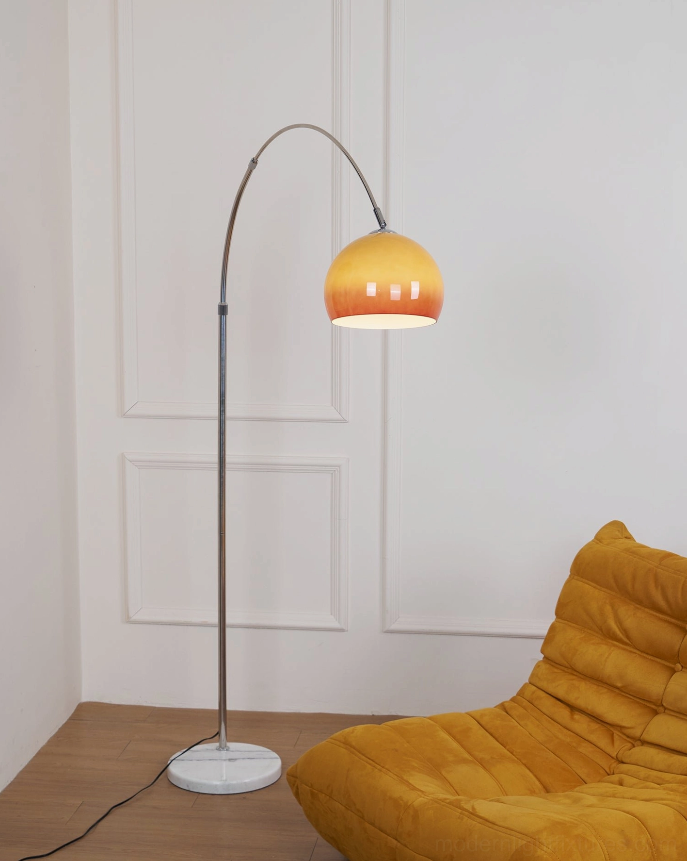 Arc floor lamp with orange spherical shade and silver pole in contemporary lounge with yellow chair