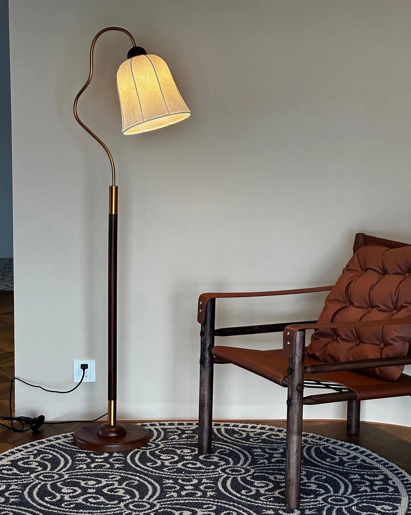 Arc floor lamp beside reading chair with warm light diffusing through beige fabric shade