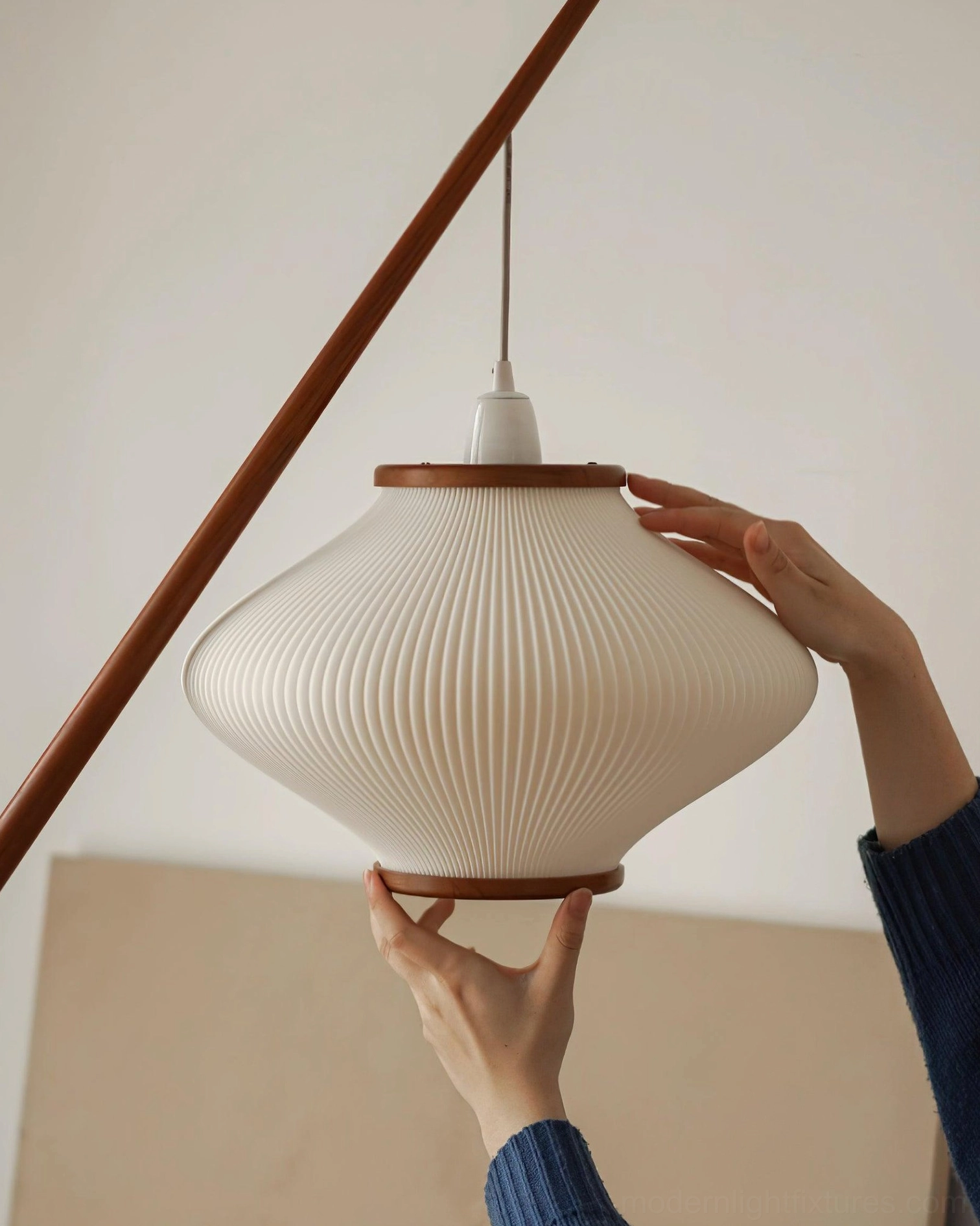 Close-up of ribbed fabric lampshade with wooden trim ring, hands holding texture detail