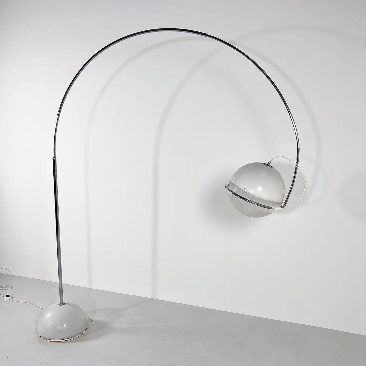 Arc floor lamp right side view with polished chrome curved frame and glowing spherical glass shade
