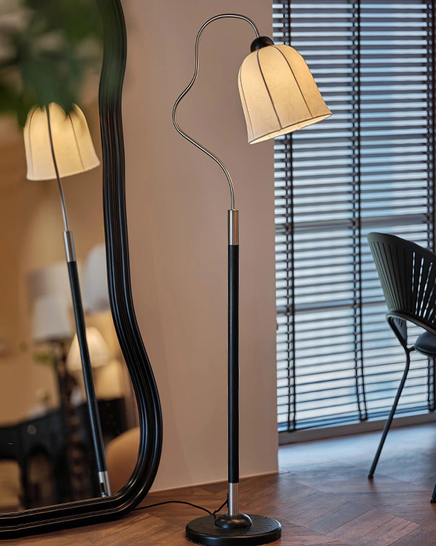 Side angle view of arc floor lamp with black metal pole, round base, soft beige fabric shade in dressing room