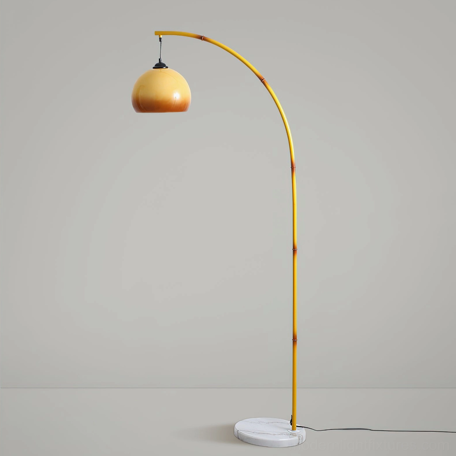Curved yellow metal arc floor lamp with marble base on gray background - side profile view