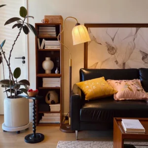 Arc floor lamp in vintage living room with leather sofa, warm glowing beige fabric shade and dark metal base