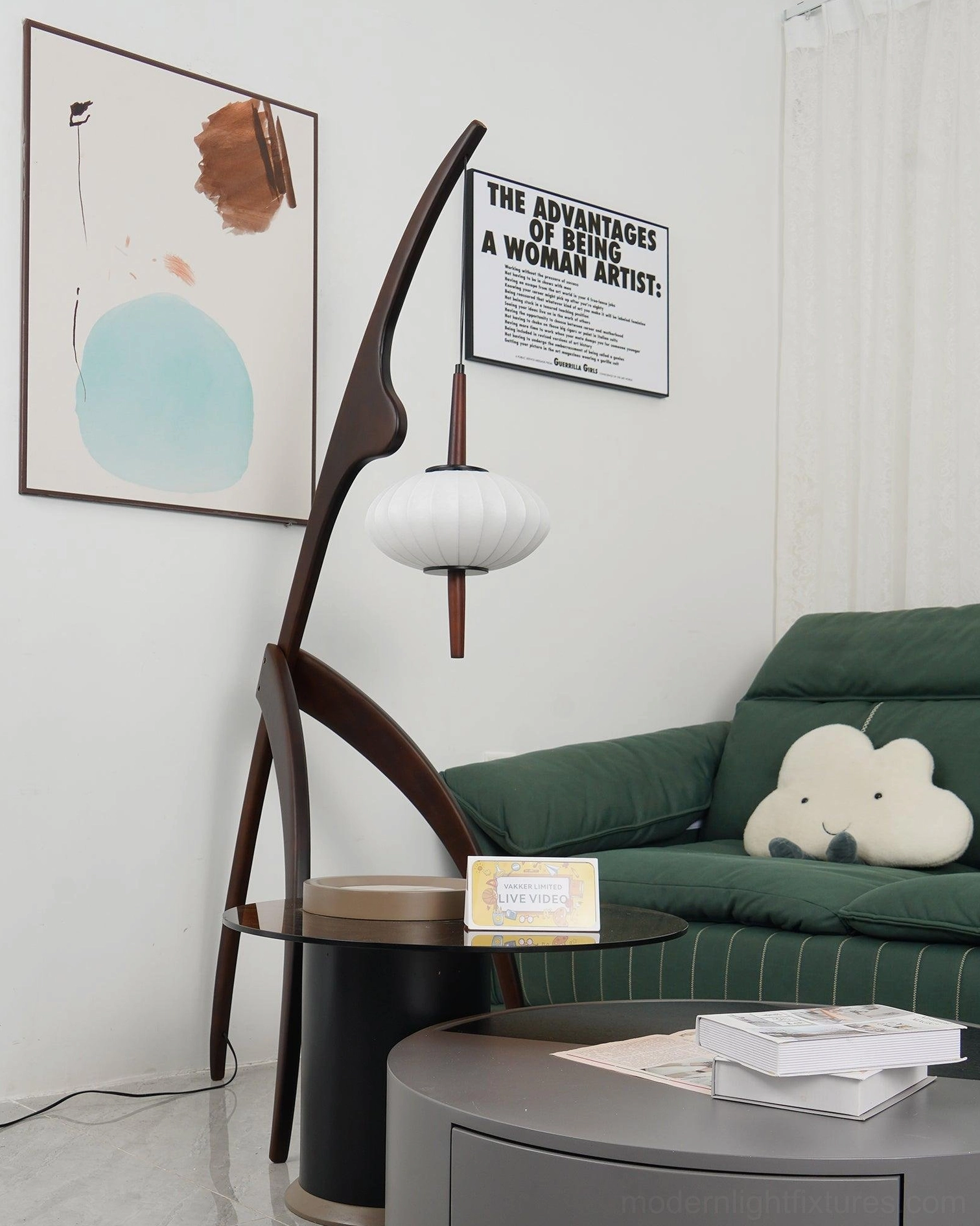 Dark walnut arc floor lamp beside green sofa with fabric lantern shade in living room with wall art