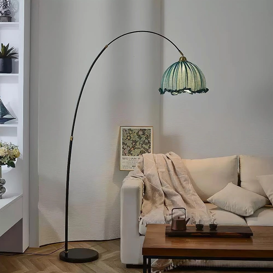 Arching floor lamp with black pole and teal ruffled shade beside cozy fabric sofa