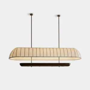 Arcelle oblong pill-shape linear chandelier with cream pleated fabric shade and dark walnut wood trim, suspended on black rods with brass-tone ceiling canopies, studio product photography