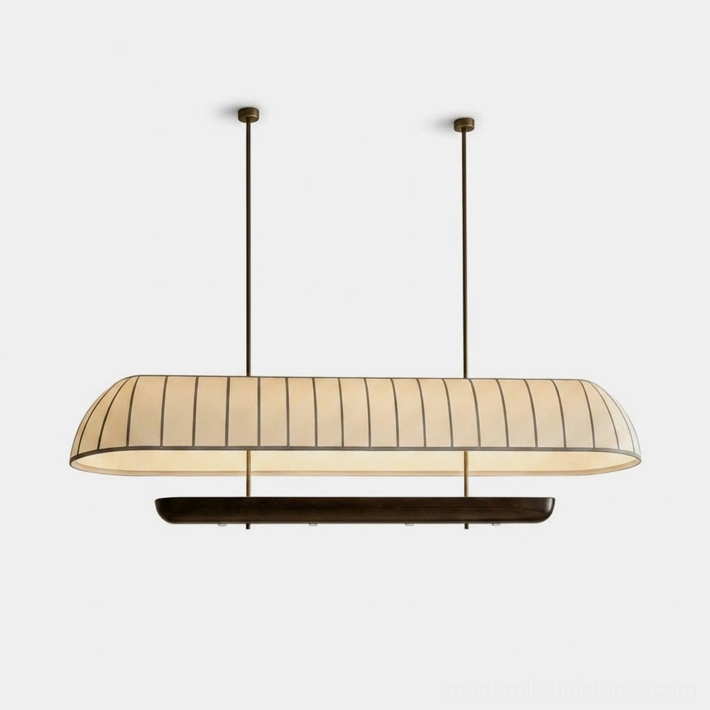 Arcelle oblong pill-shape linear chandelier with cream pleated fabric shade and dark walnut wood trim, suspended on black rods with brass-tone ceiling canopies, studio product photography
