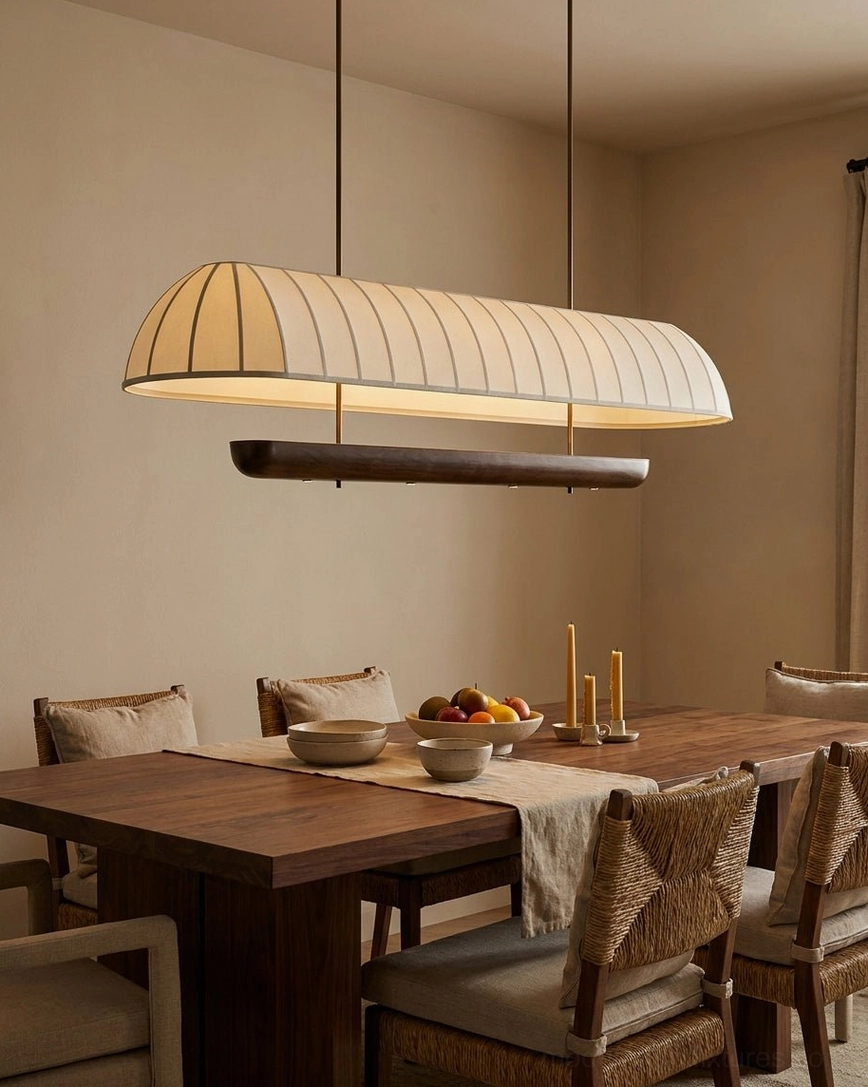 Arcelle linear chandelier side view in formal dining setting with place settings and table runner, pleated fabric shade and dark wood lower trim casting layered light patterns