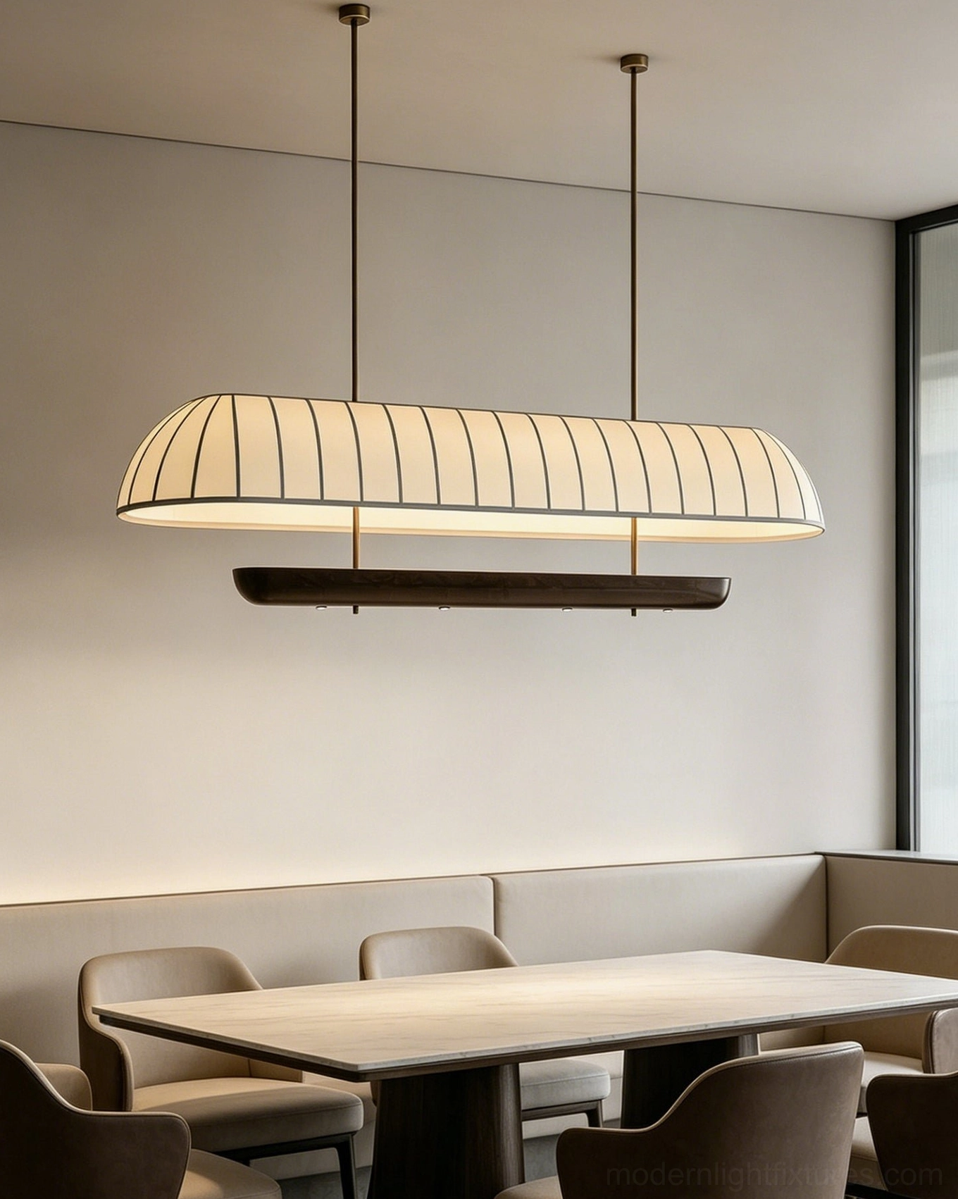 Arcelle pill-shape linear pendant light in intimate dining nook, cream pleated fabric with vertical seams and dark wood lower fixture, minimalist neutral home interior design