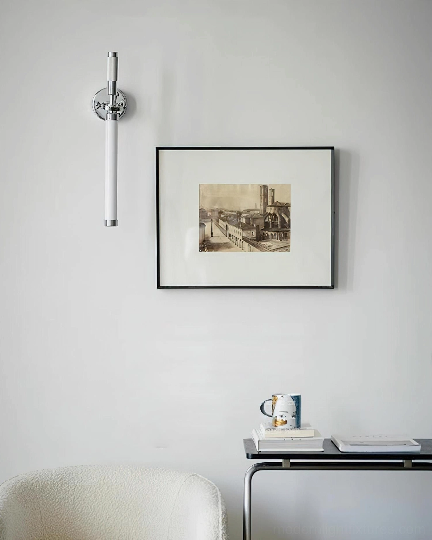 Sleek vertical Ariane wall sconce with compact chrome frame mounted on modern home wall with framed art