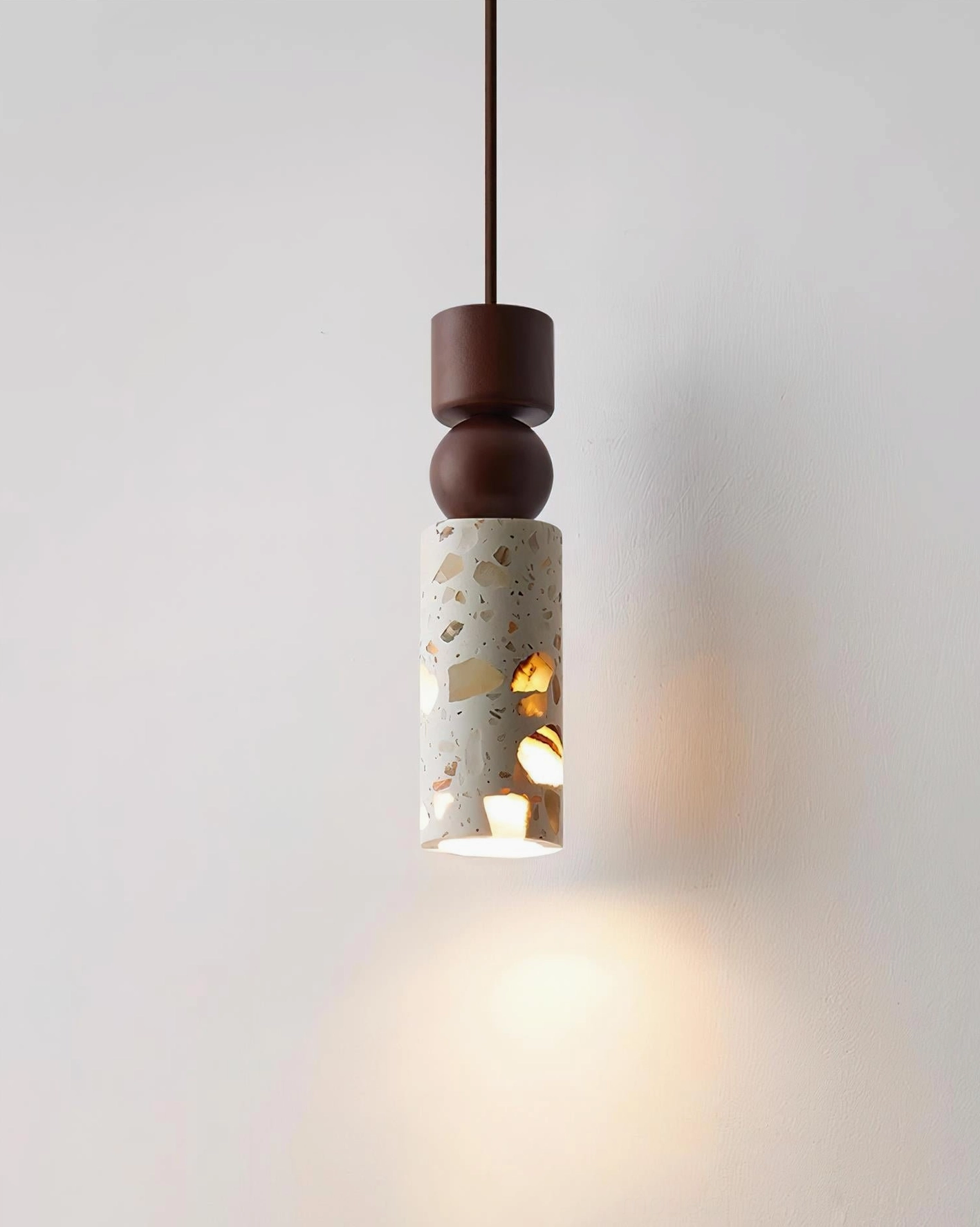 Artena modern pendant light with textured terrazzo shade and geometric cut-outs casting warm light patterns