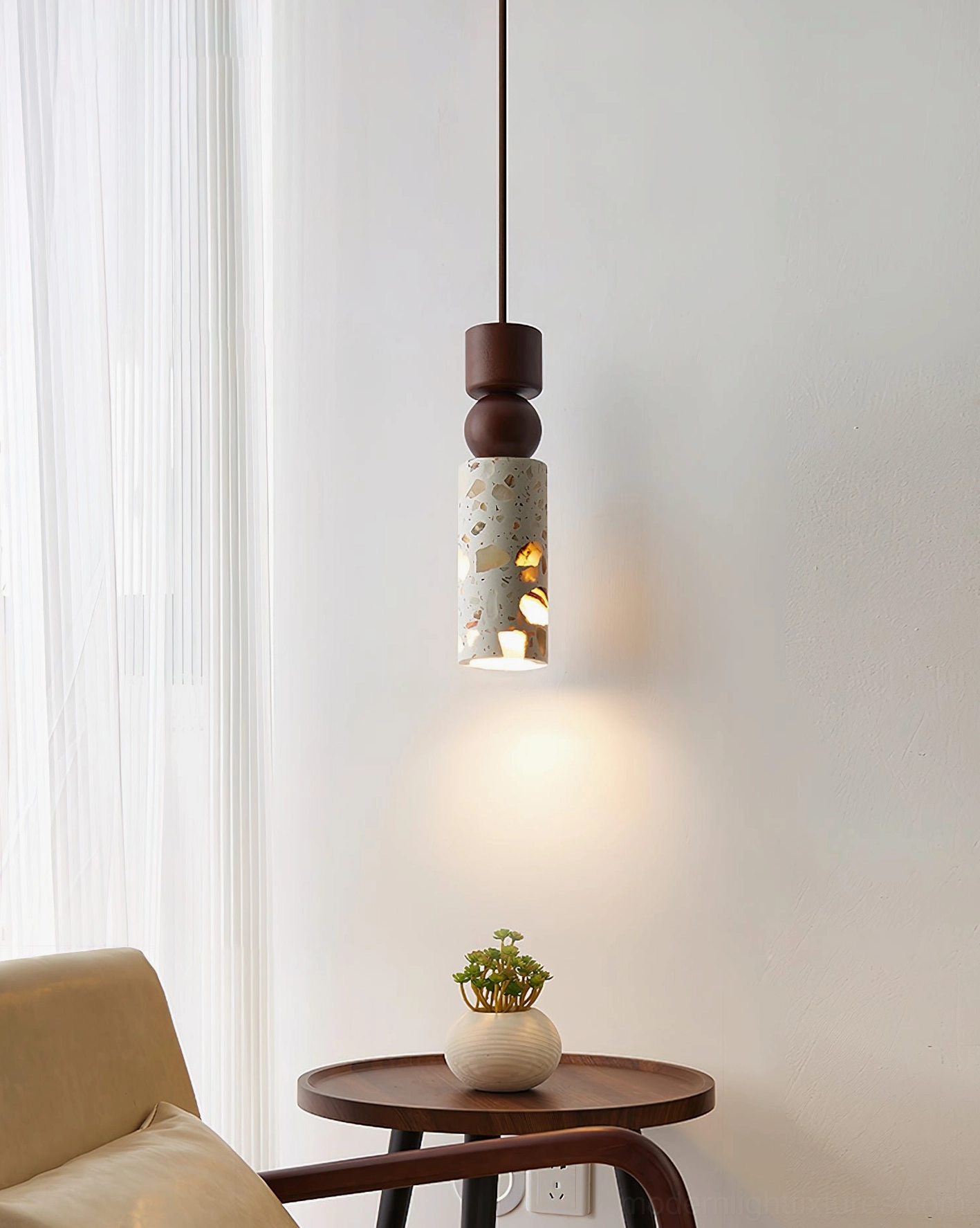 Artena modern pendant light in reading nook with accent chair and dark brown wooden cap detail