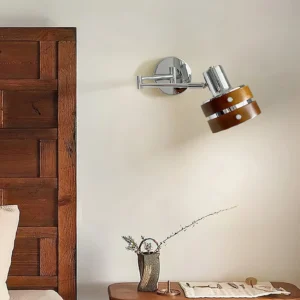 Contemporary adjustable wall lamp installed in bedroom beside wooden nightstand with decorative arrangements