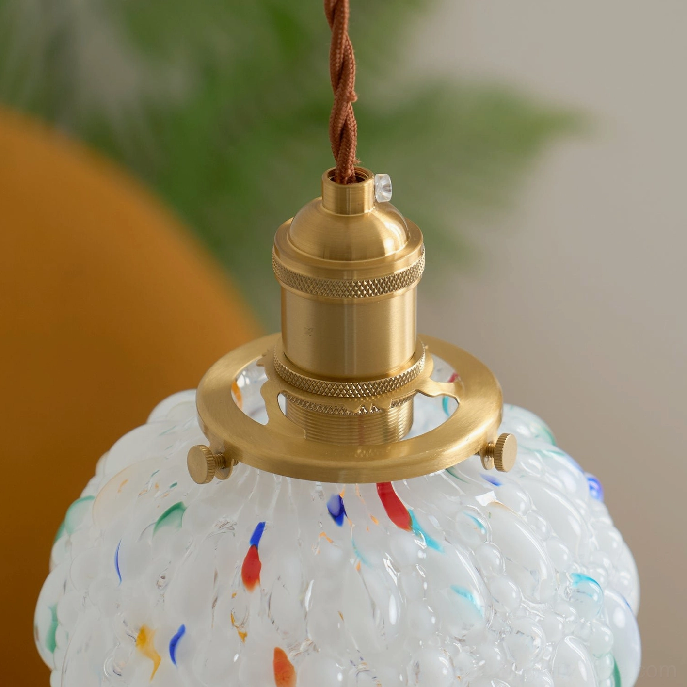 Artisan speckled glass pendant light with warm illumination, pumpkin-shaped frosted shade, polished brass mounting detail