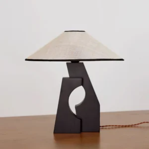 Minimalist wooden base table lamp three-quarter view on natural wood table with warm ambient lighting