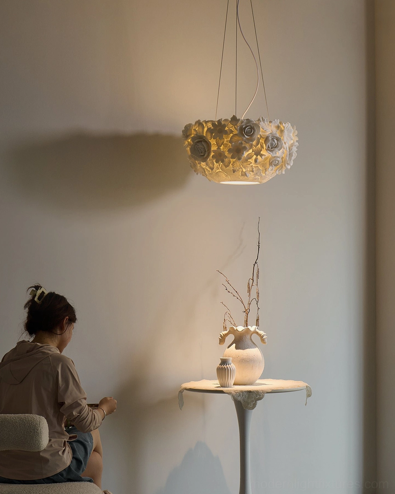 Artistic ceramic floral pendant light with intricate petal detailing, warm glow creating soft shadows on surrounding surfaces