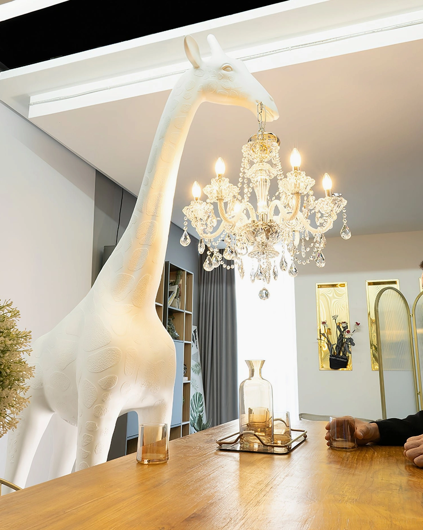 Artistic giraffe floor lamp with detailed sculptural elements and illuminated crystal chandelier creating ambient glow
