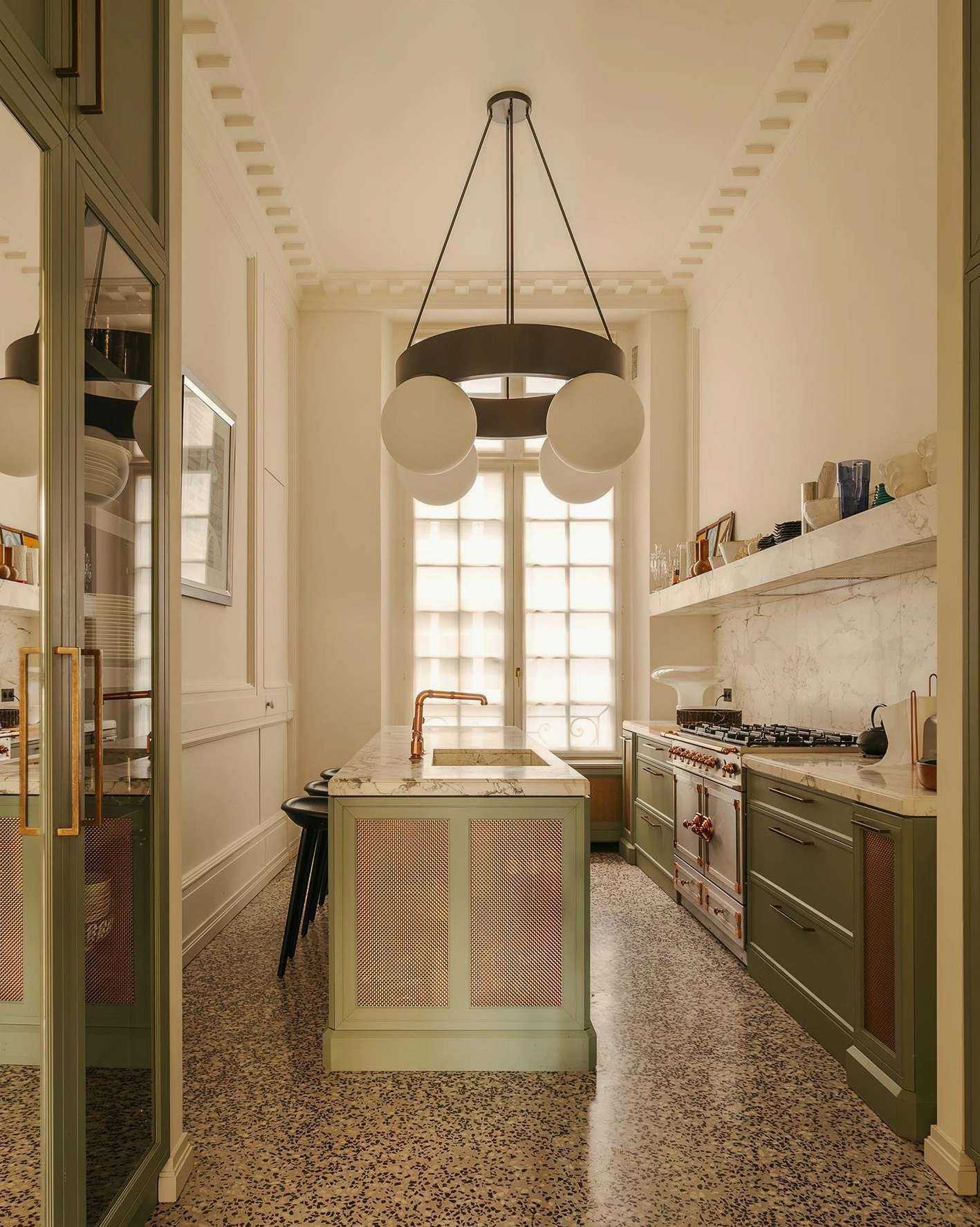 Black metal ring chandelier with frosted white glass shades above kitchen island with terrazzo flooring