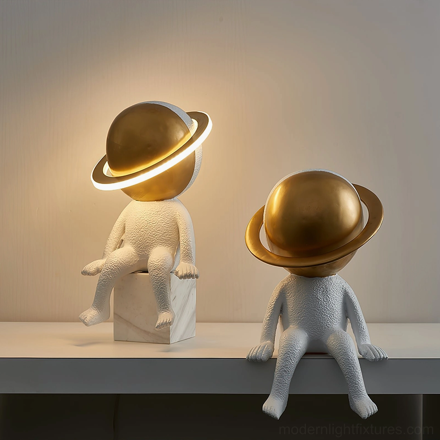 Two astronaut Halo LED lamps on dark shelf with one lamp illuminated showing minimalist space-themed design