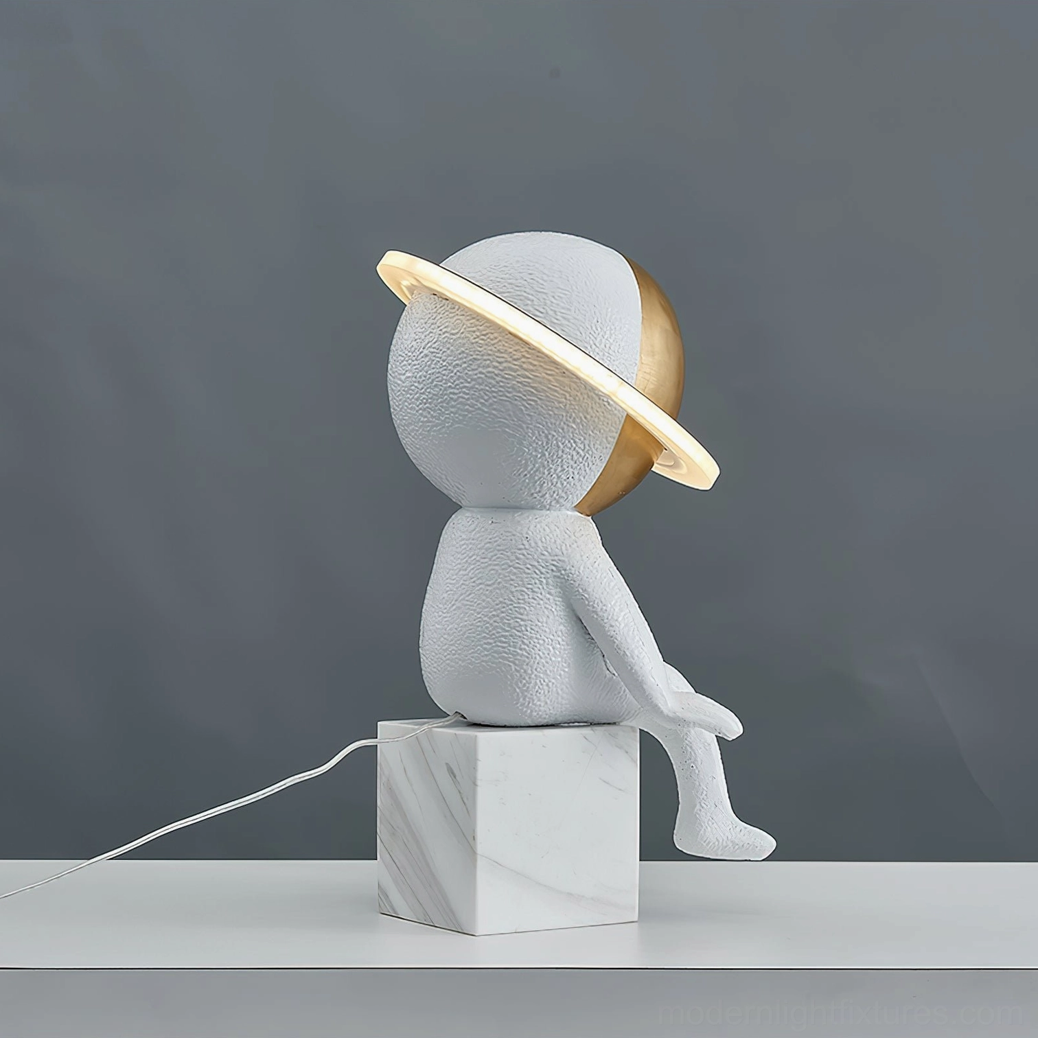 Astronaut table lamp left side profile view with power cable and marble base on grey backdrop