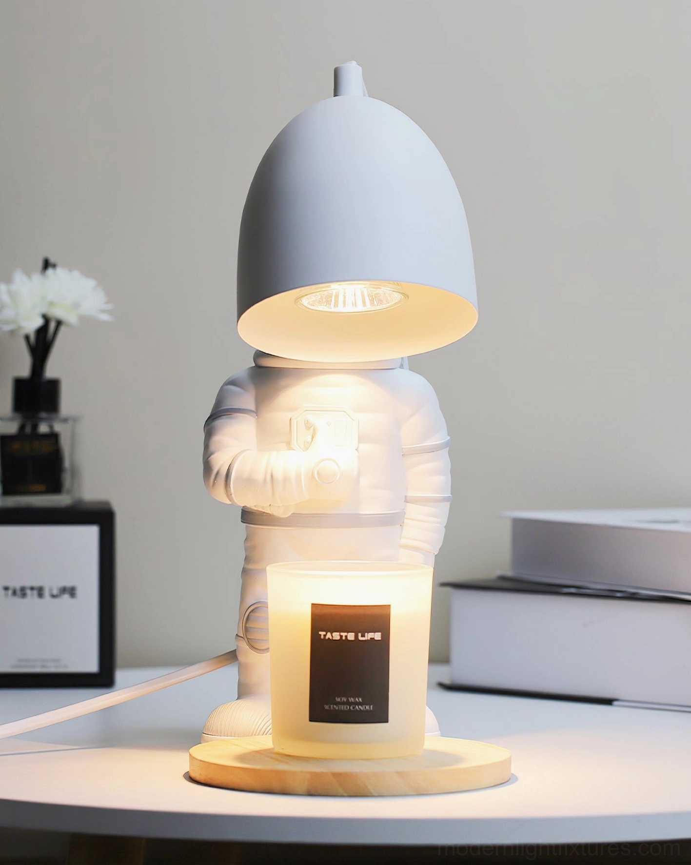 Astronaut candle warmer lamp three-quarter front view with light gray shade and floral decor on bright desk