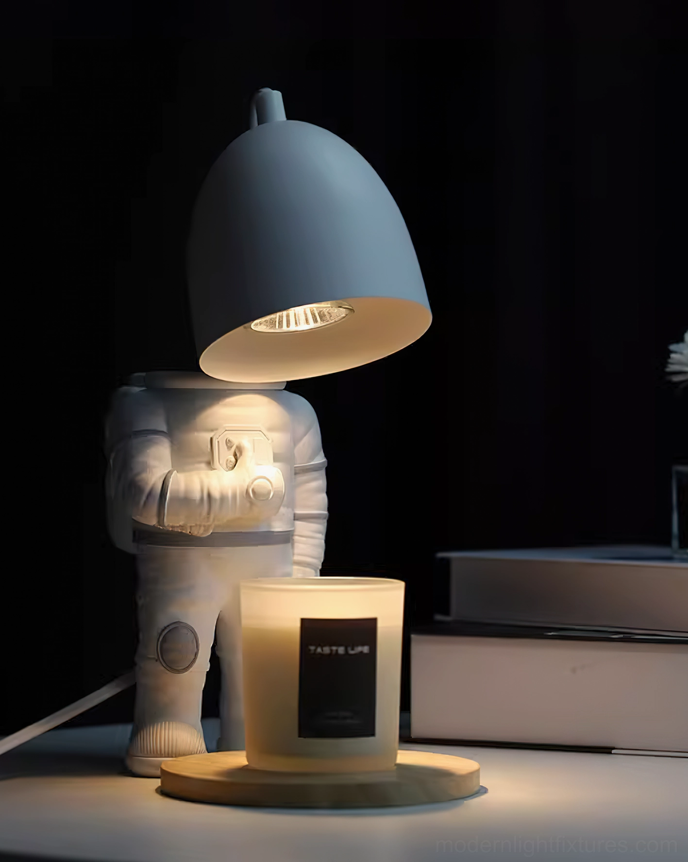 Astronaut candle warmer lamp from low side angle with dark gray shade casting warm glow in dim interior