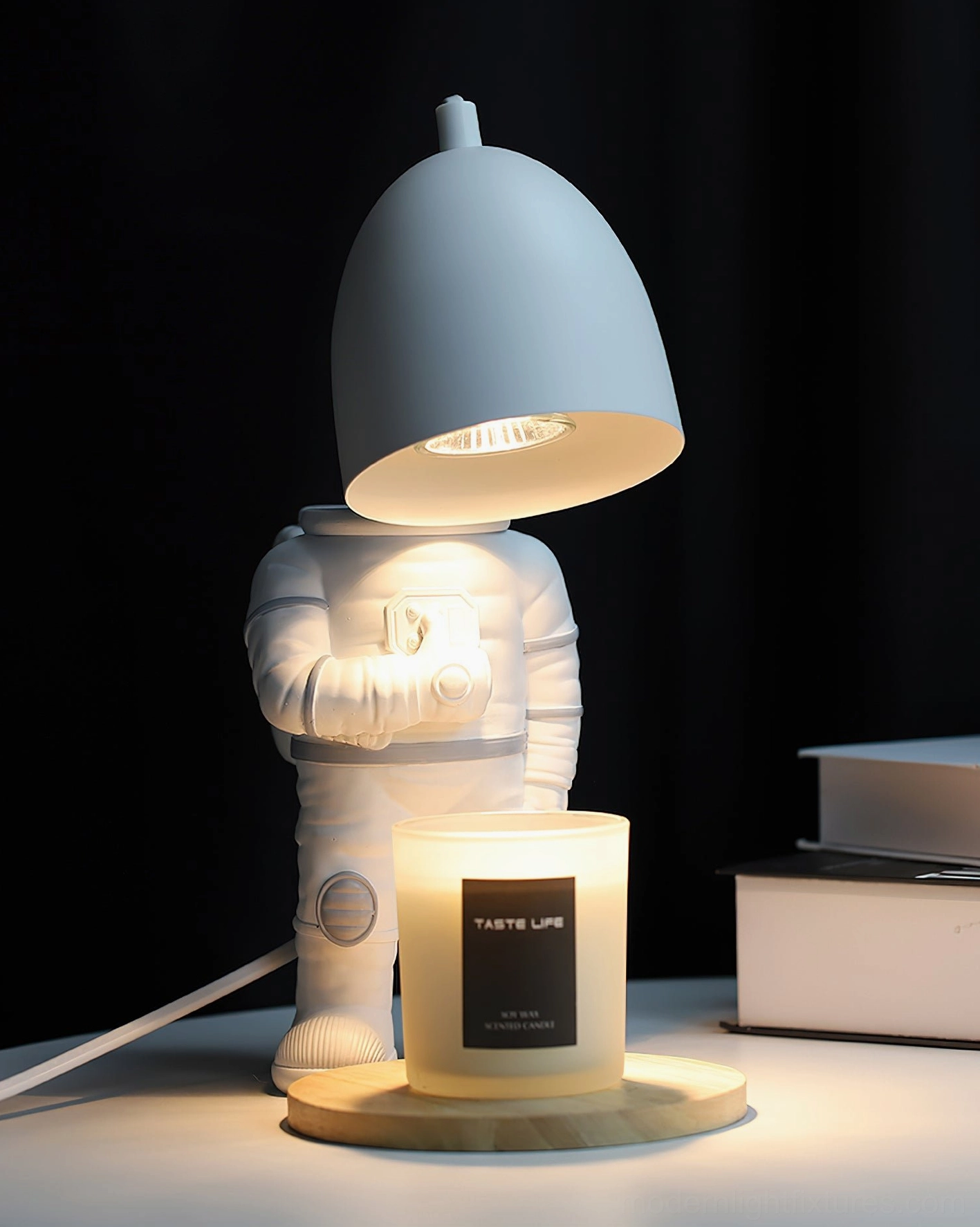 Astronaut candle warmer lamp three-quarter side view with light gray shade on desk with books