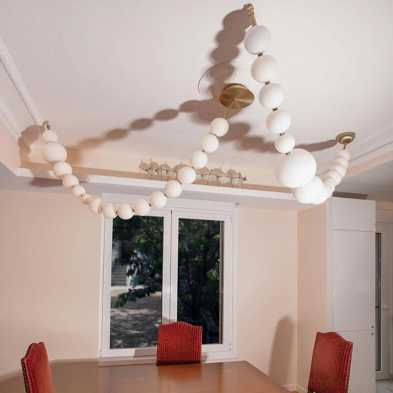 Asymmetric U-shaped pearl chandelier in residential dining room with brass metal hardware and uneven pearl arrangement