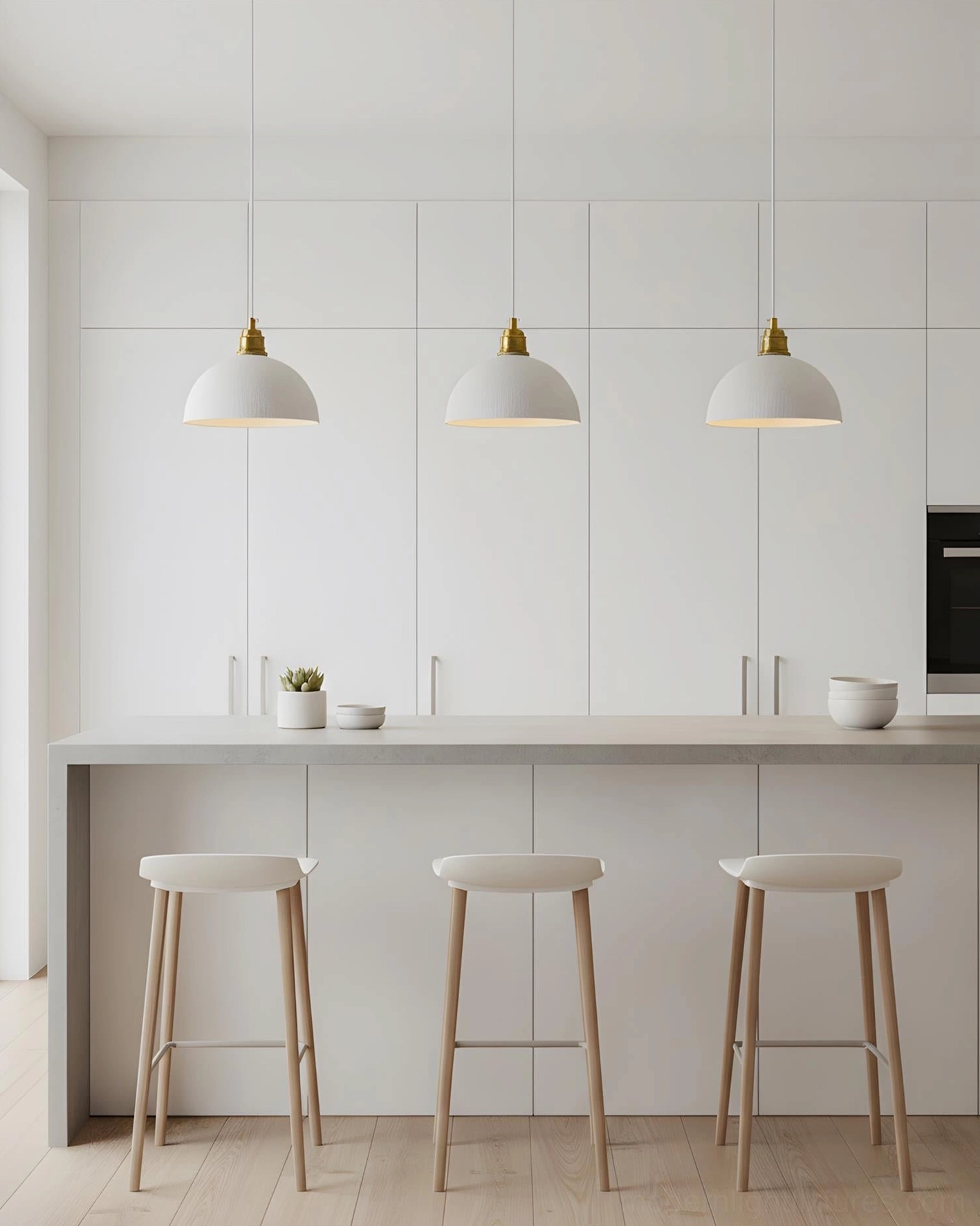 Three Aura Bell pendant lights suspended over modern white kitchen island, contemporary minimalist lighting arrangement