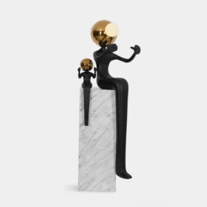 Aura sculptural floor lamp front three-quarter view with matte black resin figures, golden spherical light, and white marble pedestal