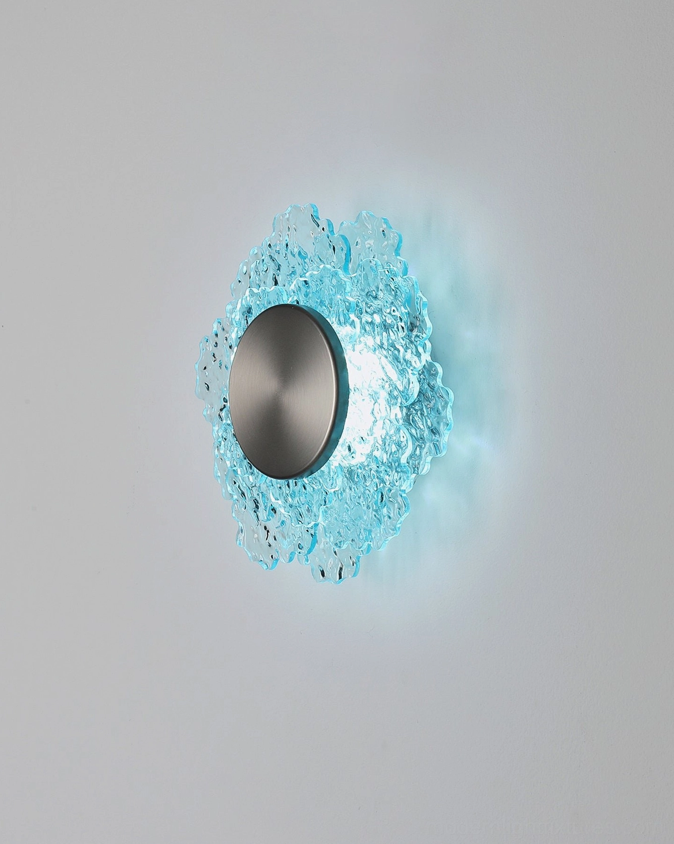 Aurelia wall sconce with ruffled cyan glass petals and brushed dark metal base, illuminated LED light