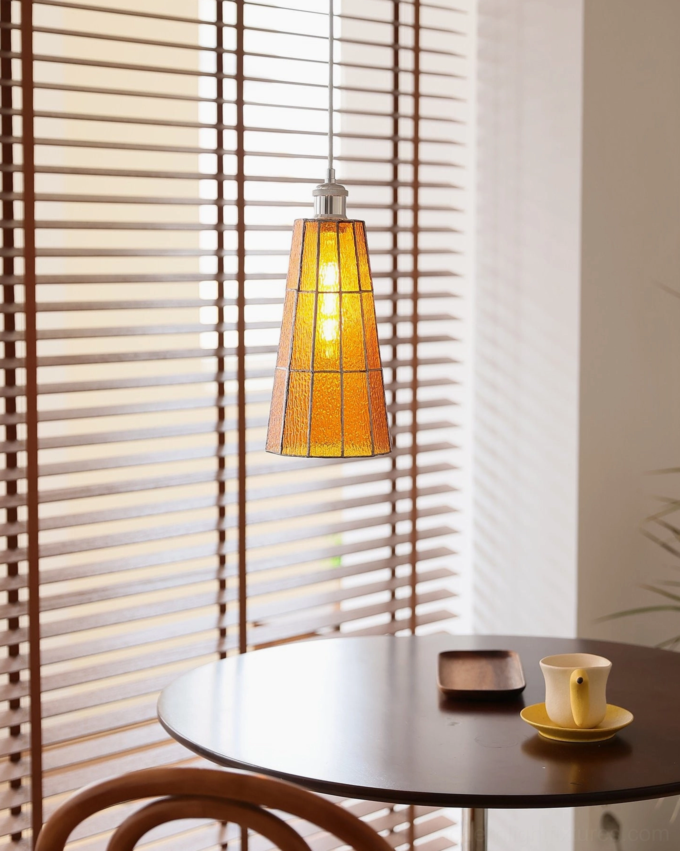 Azurielle amber stained glass pendant light over wooden dining table with natural light