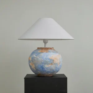 Bailey handcrafted ceramic table lamp with blue textured base and white shade on black pedestal