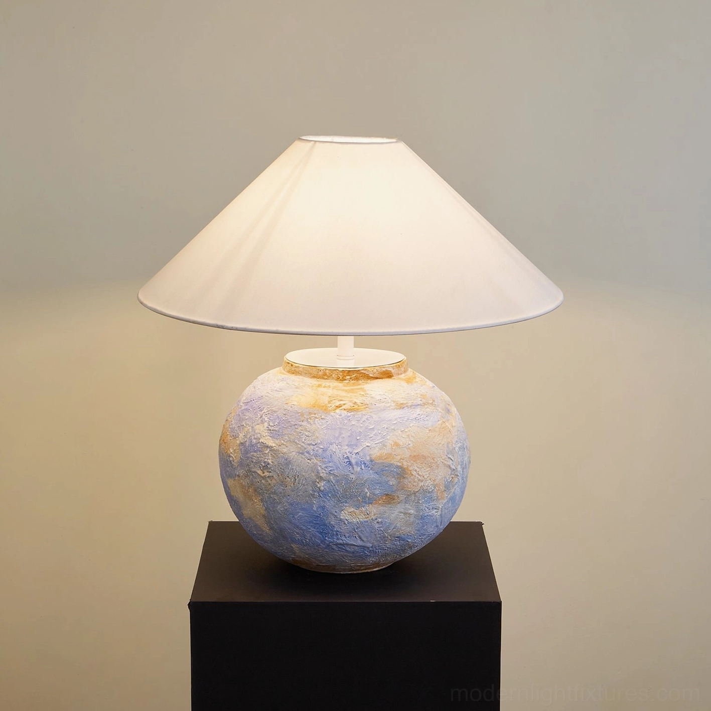 Bailey ceramic table lamp side perspective on display pedestal with warm wall backdrop