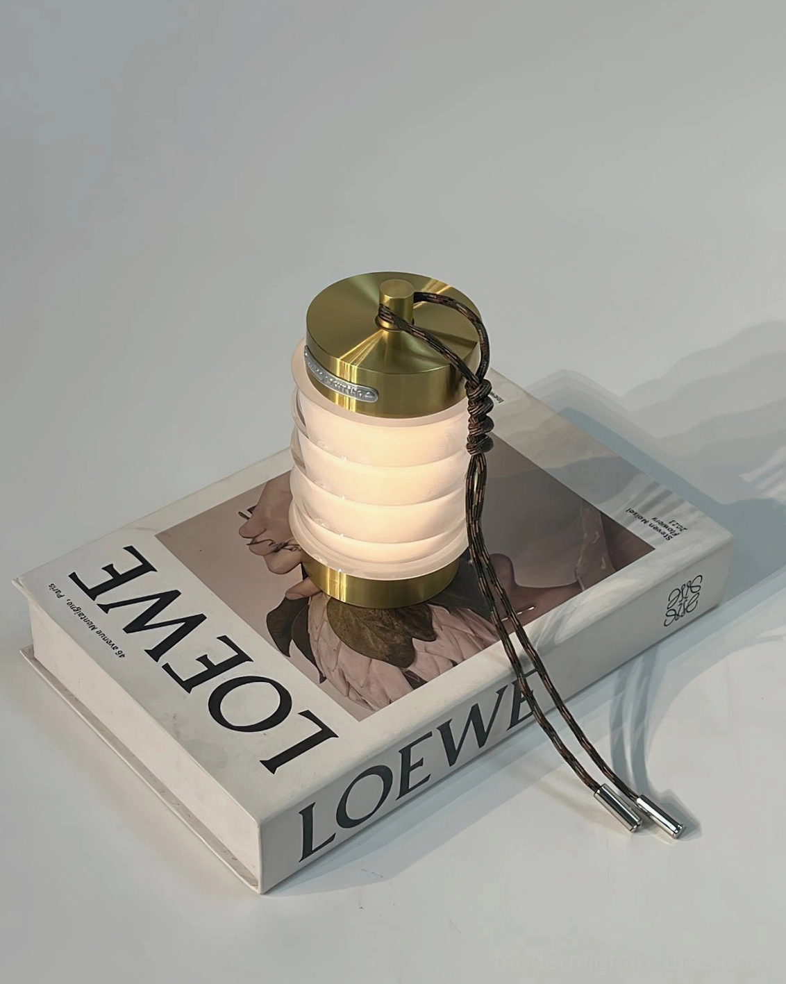 Gold finish Balia portable ambient table lamp displayed on luxury coffee table book with minimalist styling