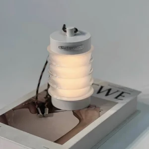 White Balia rechargeable LED table lamp with integrated carrying handle, three-quarter overhead view on fashion magazine