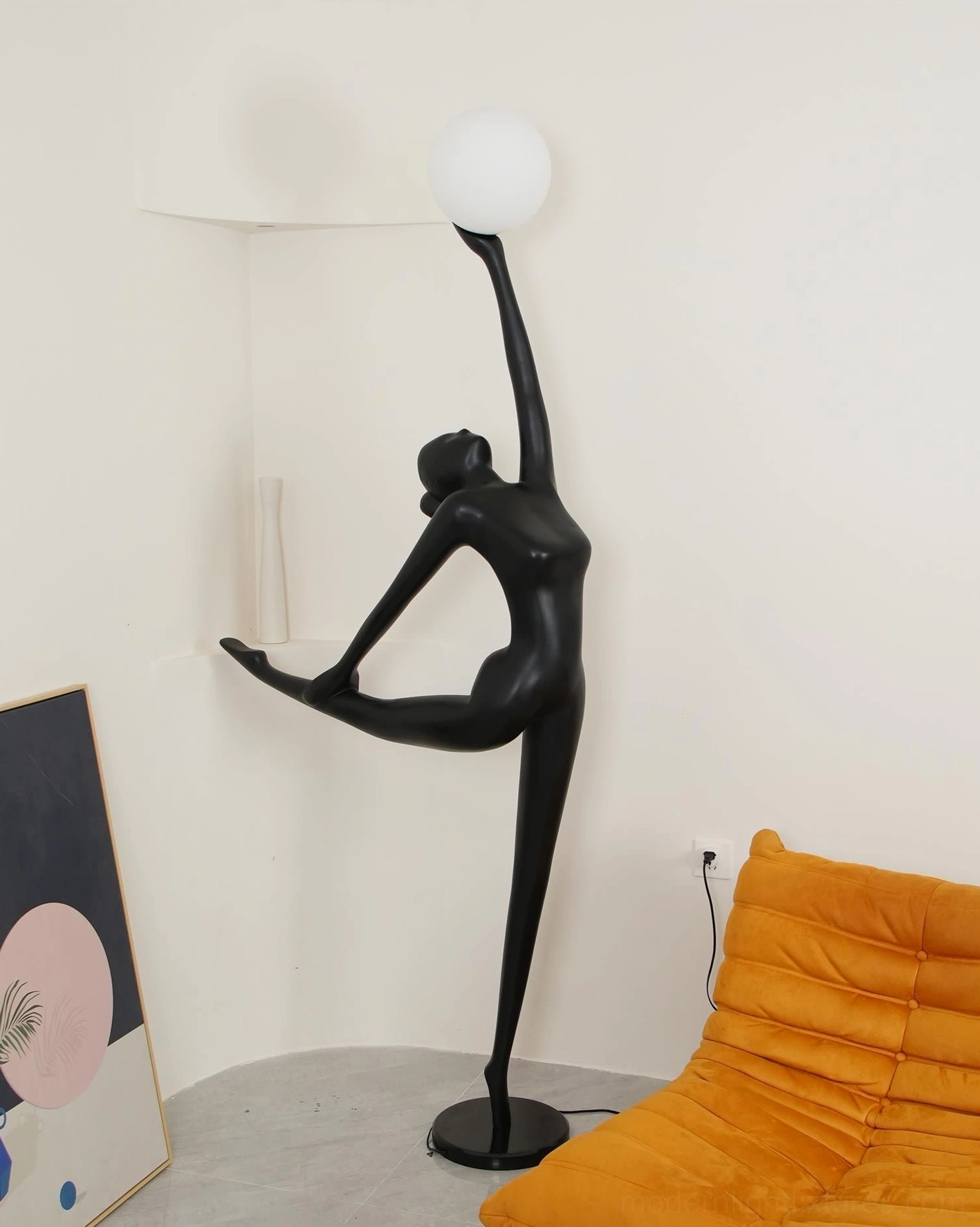 Black sculptural ballerina floor lamp in corner living room setting with wall artwork decoration