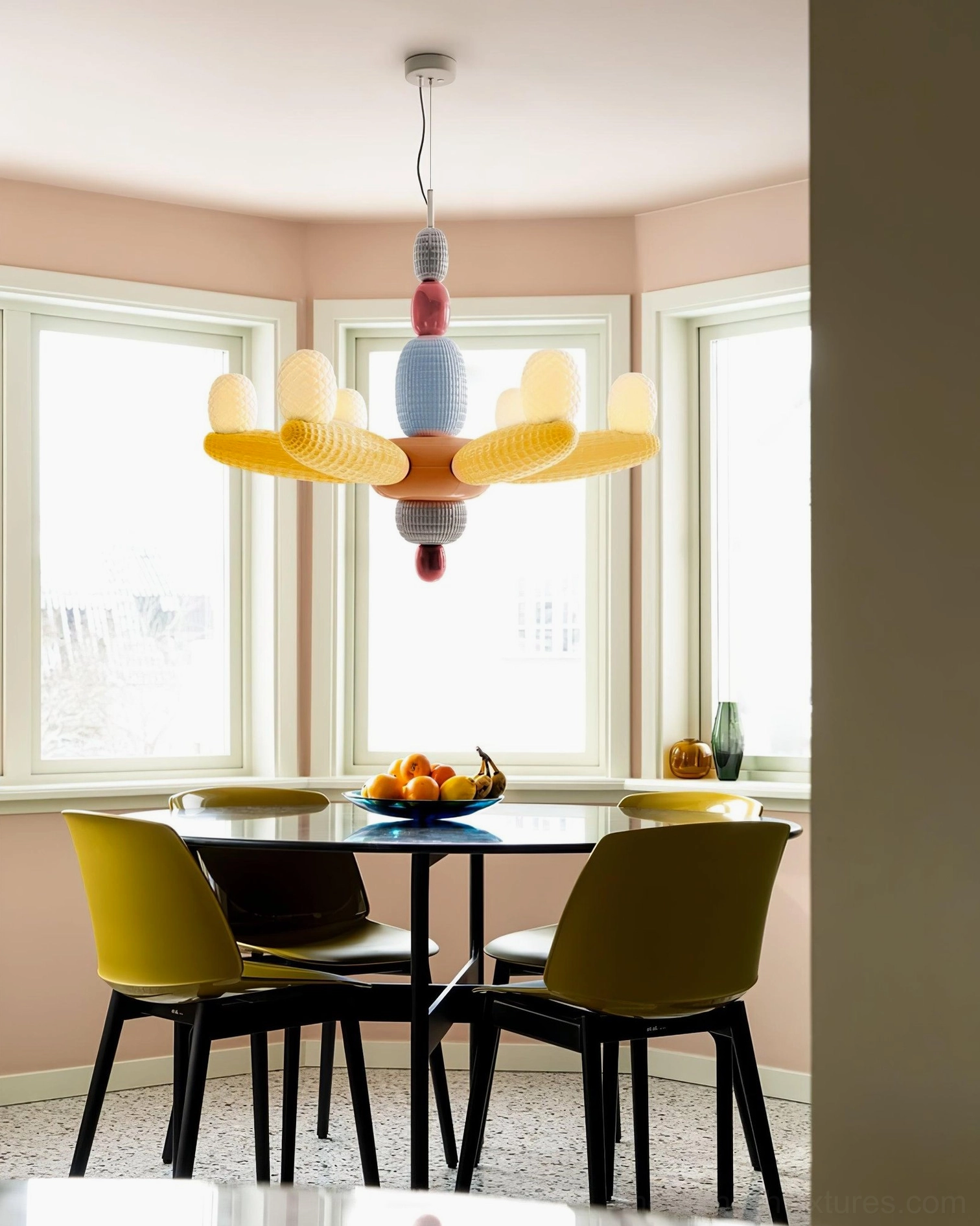 Balloon chandelier hanging above dining table in bright modern dining room with yellow chairs