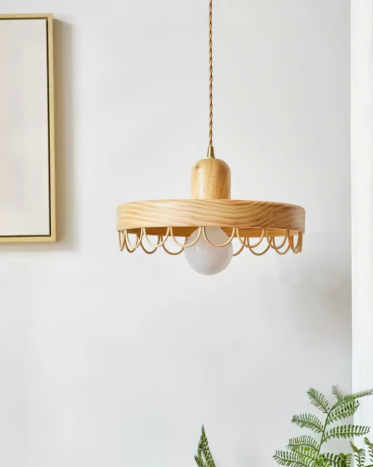 Natural wood tone pendant light with metal guard detail shown in minimalist home setting with wall art and greenery
