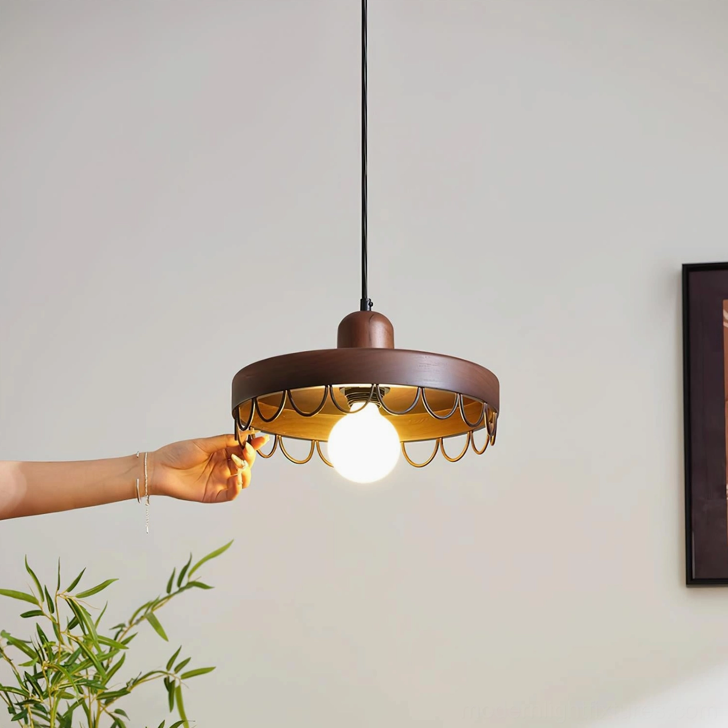 Walnut finish pendant light with black scalloped metal rim installed in contemporary home interior with plant decor