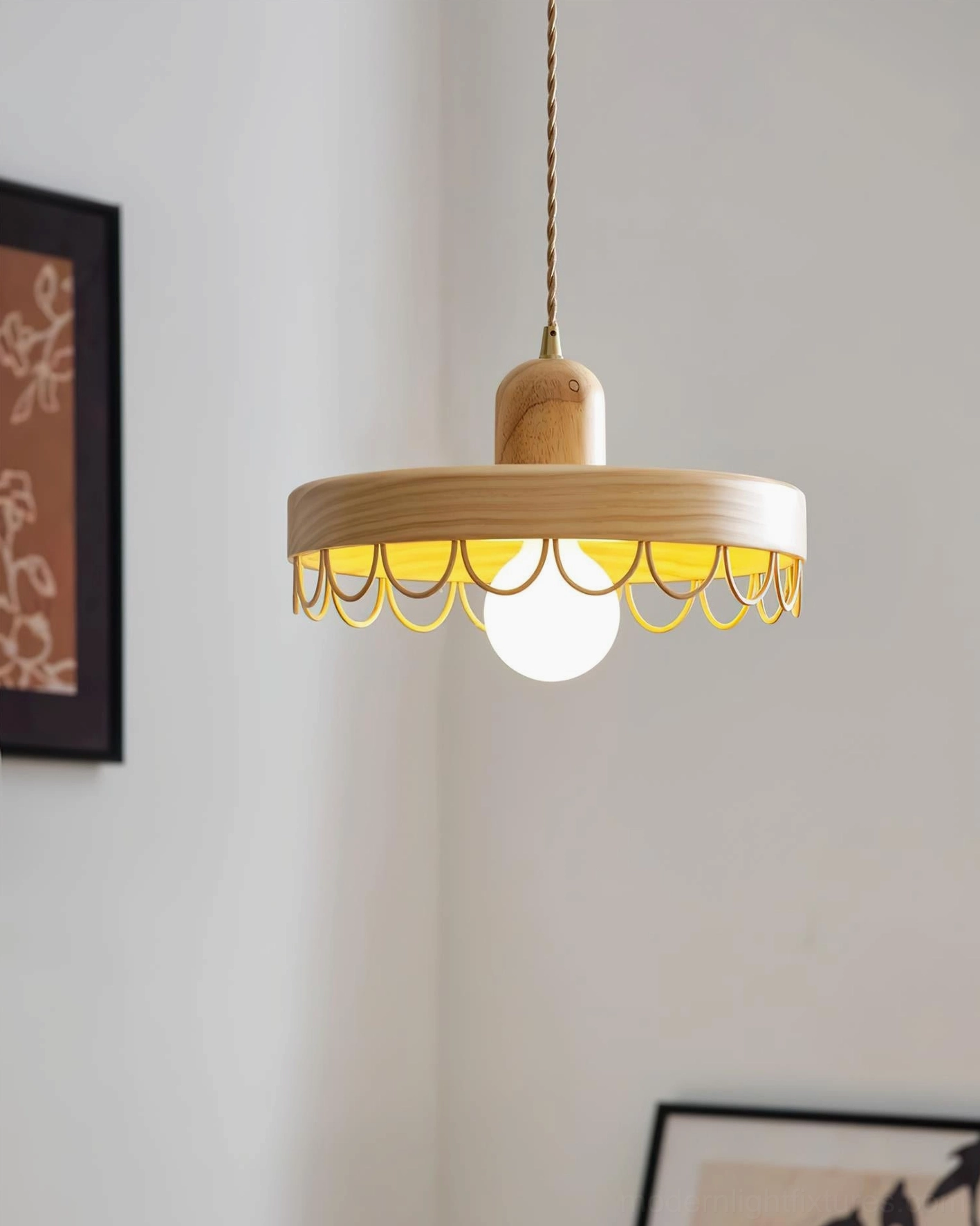 Natural wood tone pendant light with warm metal trim details installed in minimalist interior with wall decor and plant